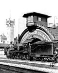 Die Saalfelder 38 1516 passiert das Wärterstellwerk "Ev" auf der Vorhalle des Empfangsgebäudes in Erfurt. Links steht der Uhrenturm der Reichsbahndirektion. Beide Bauwerke sind einzigartig. Das Stellwerk, im Eisenbahnerjargon "Storchennest" genannt, existiert heute nicht mehr. Beim Umbau des Erfurter Hauptbahnhofs wurde es 1999 außer Betrieb genommen und zurückgebaut. Die P 8 blieb nach dem Zweiten Weltkrieg in der UdSSR und wurde noch bis 1948 als Werklok eingesetzt. (1934) <i>Foto: RVM</i>