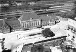 In den Jahren 1928/29 wurde eine Reihe von Städten aus der Luft fotografiert, darunter auch zentrale Bezirke wie die Bahnhöfe. Das neue, weitgehend symmetrische Aufnahmegebäude des Bahnhofs Hamm wurde im Oktober 1920 in Betrieb genommen. Während auf den Gleisen etliche Züge zu erkennen sind, wirkt der Bahnhofsvorplatz ungewöhnlich aufgeräumt. Von Anfang an war Hamm als Knotenbahnhof geplant. So wurde im Mai 1848 durch die Münster-Hammer Eisenbahn-Gesellschaft die Strecke nach Münster eröffnet und am 4. Oktober 1850 die Strecke nach Warburg über Soest und Paderborn durch die Königlich-Westfälische Eisenbahn-Gesellschaft. Schließlich eröffnete die Bergisch-Märkische Eisenbahn-Gesellschaft im Jahre 1866 ihre Strecke von Hagen über Unna. Im Zuge des Umbaus, der 1911 begonnen worden war, wurden die Gleise angehoben und der über 60 Jahre alte Bahnhof in Form eines Inselbahnhofs durch das heutige Gebäude ersetzt. Im Rahmen dieses Umbaus wurden auch zwei große Bahnbetriebswerke errichtet: Hamm P für den Personenbahnhof und Hamm G für den Rangierbahnhof, ferner ein Abstellbahnhof für Reisezüge und ein Ortsgüterbahnhof.  (1928) <i>Foto: Hansa-Luftbild</i>