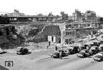 Taxistand am kriegszerstörten Empfangsgebäude des Essener Hauptbahnhofs. Links oben schiebt sich eine pr. P 8 (Baureihe 38.10) ins Bild. Der neue  Hauptbahnhof wurde im typischen Stil der 1950er Jahre wieder aufgebaut. Die 1959 fertiggestellte neue Empfangshalle lag nicht mehr vor, sondern unter den Gleisanlagen.  (1951) <i>Foto: Willi Marotz</i>