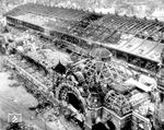 Wie dieses Bild aus dem Jahr 1945 zeigt, wurde der Kölner Hauptbahnhof während des Zweiten Weltkriegs stark beschädigt. Nach dem Krieg wurde daher einige Jahre überlegt, ob man nicht den Hauptbahnhof auf dem Gelände des Güterbahnhofs Gereon, wo sich heute der Mediapark befindet, neu errichten sollte. Daher ging der Wiederaufbau nur sehr schleppend voran und die Kölner mussten sich für ein Jahrzehnt mit Provisorien begnügen. Zunächst wurde 1953 der zerstörte westliche Langbau (links unten) durch ein modernes Gebäude mit Gepäckabfertigung und Hotel ersetzt. Das nur gering zerstörte und provisorisch reparierte alte Empfangsgebäude (rechts) wurde erst 1955 abgerissen. Einer der vermeintlichen Gründe hierfür war angeblich die Beseitigung des Gebäudes als Symbol der preußischen Herrschaft. Auch ein Abriss der Bahnsteighalle, ähnlich wie am Bahnhof Köln-Deutz, war geplant, da durch den Ruß der Dampflokomotiven die Dachkonstruktion stets stark verschmutzt war. Der Abriss wurde jedoch aus Kostengründen nicht realisiert; 1957 begann die Elektrifizierung des Hauptbahnhofs und sorgte für Abhilfe dieses Problems.  (1945) <i>Foto: Pressefoto ACME</i>