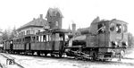 Eine neue Epoche ist im Bahnhof Mudau angebrochen. Die frühere Lok 4 heißt jetzt 99 7204 und trägt auf dem Kessel nunmehr einen "Großturbogenerator" für die Lok- und Zugbeleuchtung, sowie den großen genieteten Hauptluftbehälter für die Westinghouse-Druckluftbremse, welche die Körting-Saugluftbremse abgelöst hat. Die ehemaligen 2./3.-Klasse-Wagen führen jetzt ausschließlich die 3. Klasse, hinter ihnen läuft der kleine, nach dem 1. Weltkrieg von Ettenheimmünster hierher gekommene Packwagen, am Zugschluß hängt einer der mittlerweile zehn vorhandenen Rollwagen mit einem normalspurigen Rungenwagen.  (1931) <i>Foto: DLA Darmstadt (Maey)</i>