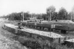 Herbstzeit – Kartoffelzeit, das bedeutete Hochbetrieb sowohl auf den Kleinbahnen als auch auf der Werkbahn der 1873 gegründeten Kyritzer Stärkefabrik. Die am 7.12.1907 in Dienst gestellte werkseigene Motorlok der Deutz-Type C XII F hält für den Fotografen auf der Kreuzung mit der Normalspurstrecke Meyenburg – Neustadt (Dosse) mit einem Leerzug, den sie in den Kleinbahnhof drückt. Im Vordergrund steht der nächste Kartoffelzug abholbereit. Nachdem das schmalspurige Anschlußgleis bereits in den 1960er Jahren stillgelegt worden war, fuhren die normalspurigen Kartoffelzüge noch bis 1985 durch die Wilsnacker Straße (Gleisreste liegen noch heute in der Straße), dann wurden die werksinternen Gleise über eine weiträumige Umgehung von Norden her angebunden. Nach der Wende wurde das Gleisnetz aufwendig umgebaut, aber nach der Übernahme durch die Emsland-Stärke GmbH (1991) nicht wieder in Betrieb genommen.  (1963) <i>Foto: Sammlung Ludger Kenning</i>