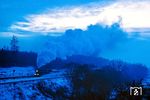 Eine 44er fährt zur "blauen Stunde" durch Blankenheim. Die "blaue Stunde" bezieht sich auf die besondere Färbung des Himmels während der Zeit der Dämmerung nach Sonnenuntergang bis zum Eintritt der nächtlichen Dunkelheit. In der analogen Fotografie war das Fotografieren eines fahrenden Zuges zwischen Tag und Nacht schon eine Herausforderung, konnte man den Kodachrome 25-Diafilm nicht mal eben auf eine hohe ASA-Zahl hochschrauben. Die besondere Stimmung macht dabei durchaus die Bewegungsunschärfe wett. (02.1978) <i>Foto: Dr. Uwe Knoblauch</i>