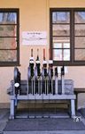 Das mechanische Außenstellwerk im Bahnhof Bad Kohlgrub, der als Kreuzungsbahnhof lediglich über Einfahrsignale verfügte. Es ging 1950 in Betrieb und wurde 2008 mit Inbetriebnahme des EStw Murnau ersetzt. Der Hebel der Weiche 4 (zweiter von links) führte zum Ladegleis mit dem darüber angebrachten Hinweisschild "zuerst einschalten", was bedeutete, dass die Oberleitung über dem Ladegleis zuerst unter Strom zu setzen war, da das Gleis in Grundstellung stromlos war. Die Weichen 1 (ganz links) und 5 waren die beiden Einfahrweichen des Bahnhofs; Weiche 1 aus Richtung Grafenaschau, Weiche 5 aus Richtung Saulgrub. Die beiden roten Hebel waren die Einfahrsignale ("A" von Grafenaschau, "D" von Saulgrub). Ganz rechts auf der Hebelbank befinden sich die beiden Fahrstraßenhebel. Die Schrankenkurbel für den Bahnübergang an der Ausfahrt Richtung Oberammergau ist hier nicht mehr im Bild. (27.03.1981) <i>Foto: Prof. Dr. Willi Hager</i>