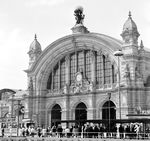 Das Empfangsgebäude des Frankfurter Hauptbahnhofs ist wurde im Stil der Neorenaissance gestaltet, die Erweiterungen des Empfangsgebäudes von 1924, den beiden äußeren Hallen vorgelagerten in neoklassizistischem Stil. Das Gebäude ist 270 Meter breit. Die Mitte des Empfangsgebäudes bildet die Hauptempfangshalle (Foto), deren straßenseitiger Eingang aus drei Türeinheiten gebildet wird, die durch zwei mächtige Pfeiler geteilt werden. In der Mitte darüber befinden sich eine verzierte Uhr mit den Allegorien von Tag und Nacht. Zu beiden Seiten der Fassade befindet sich je ein Turm. Auf der Dachmitte steht eine 6,3 Meter hohe in Bronze getriebene Figurengruppe des Braunschweiger Bildhauers Gustav Herold: Atlas, der die Weltkugel auf seinen Schultern trägt, begleitet von Symbolfiguren für Dampf und Elektrizität. Außerdem finden sich Figuren zu Handel und Ackerbau und zu Eisenindustrie und Schifffahrt.  (1966) <i>Foto: Reinhold Palm</i>