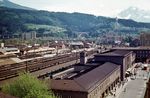 Blick auf den 1858 eröffneten Innsbrucker Hauptbahnhof mit dem 1956 eröffneten schlichten, aber funktionalen Empfangsgebäude. Links befindet sich der Frachtenbahnhof (der eigentliche Innsbrucker Verschiebebahnhof befindet sich in Hall in Tirol), zwischen Personen- und Güterbahnhof das Bw (Zfl Innsbruck). An dem Viadukt der A 13 (Bildmitte oben) führt die Brennerstrecke in einem Tunnel unter der Schanze des Bergisel hinauf zum 1370 m hoch gelegenen Übergang über den Alpenhauptkamm am Brenner (rechts oben). (1975) <i>Foto: Hans-Jürgen Müller</i>