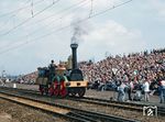 Vom 07. bis 09. April 1989 fanden rund um Riesa Veranstaltungen zum 150sten Jubiläum der ersten deutschen Ferneisenbahn von Dresden über Riesa nach Leipzig statt. Vor der Zuschauertribüne in Riesa fährt die "Saxonia" vorbei. Die "Saxonia" der Leipzig-Dresdner Eisenbahn-Compagnie war die erste funktionstüchtige in Deutschland gebaute Dampflok. Sie wurde 1838 in der Maschinenbauanstalt Übigau bei Dresden gebaut, 1843 nach über 8000 Kilometern Laufleistung zur Reservelok herabgestuft und 1849 verschrottet. Anlässlich des 150. Jubiläums der Einweihung der Bahnstrecke erfolgte in den 1980er Jahren ein Nachbau. Dabei wurde die Konstruktion und Fertigung des Nachbaukessels dem VEB Dampfkesselbau Übigau in Dresden anvertraut. Damit baute der Betrieb fast genau 150 Jahre nach dem Original-Kessel nun auch den modernen Nachbau.  (09.04.1989) <i>Foto: Joachim Schmidt</i>