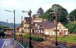 Als wäre die Zeit in Wuppertal-Beyenburg stehengeblieben. Der Blick geht von der Kurvenstraße auf das Bahnhofsensemble aus dem Jahr 1888, das aus vielen Teilen besteht und recht verwinkelt daherkommt. Neben dem Empfangsgebäude einschließlich Fahrdienstleiterraum, sind Gaststätte, der Verwaltungsteil mit Durchgang, ein Toilettenhäuschen und der ganz links anschließende Güterschuppen auszumachen. Das als Baudenkmal geführte Empfangsgebäude ist heute noch vorhanden. (31.05.1978) <i>Foto: Wilfried Sieberg</i>