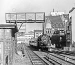 01 0510 mit D 336 nach Hamburg auf der Stadtbahn am Bahnhof Berlin-Savigniplatz mit Blick auf den Tattersall (rechts). Der Name Tattersall, ursprünglich aus dem Englischen, geht auf eine Reitschule mit Pferdevermietung zurück, die ab 1893 ihren Standort zwischen der Uhland- und Grolmannstraße hatte. Über den Räumlichkeiten des heutigen Lokals Diener Tattersall befand sich seinerzeit ein Casino mit Gesellschaftsräumen, in dem bisweilen auch Kaiser Wilhelm II. pausierte. 1954 übernahm der Boxer Franz Diener, ehemaliger Meister im Schwergewicht, die Lokalitäten und gab den Räumen seinen Namen. Sehr schnell entwickelte sich der "Diener Tattersall" zu einer bekannten Künstlerkneipe, die nicht nur für ihre hausgemachte Leberwurst bekannt war, sondern auch für ihren wöchentlichen Künstlerstammtisch. Auch nach dem Tode Dieners blieb man dann der Tradition des "Diener Tattersalls" als Künstlerlokal treu. Selbst das Mobiliar mit seinen Holztischen und schlichten Stühlen ist bis heute geblieben. Inzwischen zieren über 500 Bilder und Autogramme bekannter Schauspieler die Wände des Lokals, die hier zu Gast waren, wie Billy Wilder, Helmut Newton oder Rainer Fassbinder. Ein Grund für die Beliebheit des Lokals war und ist sicherlich die angebotene zünftige Küche. Noch heute bekommt man passend zum Ambiente "Strammen Max", Bauernsülze mit Bratkartoffeln oder Matjesfilet mit einem Bier angeboten. Nicht wenige Berliner behaupten, im "Diener Tattersall" gäbe es die besten Bouletten der Stadt. (1976) <i>Foto: Karsten Risch</i>