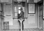 Die Fahrkartenausgabe im ursprünglichen Empfangsgebäude von 1879 des Bahnhofs Mannheim-Waldhof. 1936 wurde das alte Gebäude durch einen sehr modernen, in expressionistischen Formen als kubischer Klinkerbau, ersetzt. Markant war sein gläserner Turm, der die zentrale Eingangshalle belichtete. Das Bauwerk überstand den Zweiten Weltkrieg weitgehend unversehrt. 1982 wurde es in Vorbereitung auf den Bau der westlichen Einführung der Riedbahn abgerissen.  (11.1933) <i>Foto: RBD Mainz, Slg. W. Löckel</i>