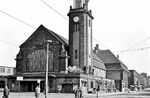Nachdem Hagen bereits 1848/49 an das Bahnnetz angeschlossen wurde, musste für die aufstrebende Industriestadt bald ein repräsentatives Empfangsgebäude gefunden werden. Am 14. September 1910 wurde das neue, im neobarocken Stil vom Architekten Walter Morin geplante Empfangsgebäude eingeweiht. Das aus Ziegelsteinen gebaute und teilweise mit Sandstein verkleidete Gebäude überstand den Bombenhagel des Zweiten Weltkriegs zwar nicht unversehrt, wurde im Gegensatz zu anderen Bahnhöfen im Ruhrgebiet aber nicht vollständig zerstört. Über dem Eingang blieb auch das Glasgemälde „Der Künstler als Lehrer für Handel und Gewerbe“ erhalten. (24.08.1958) <i>Foto: Karl-Ernst Maedel</i>