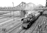 65 1043 vom Bw Dresden Altstadt fährt mit einem Güterzug durch Dresden Hbf. Die Hohe Brücke über dem Zug führte von der Bismarckstraße, der heutigen Bayrischen Straße, über die westlichen Bahngleise des Hauptbahnhofs zur Kohlschütterstraße. Benannt wurde die Brücke seit 1894 nach der in ihrer Nähe beginnenden Hohen Straße. Über diese Brücke fuhr auch die Straßenbahnlinie 6 zur Bergstraße nach Räcknitz. Ende der 1960er Jahre musste die Brücke der Elektrifizierung des Hauptbahnhofs weichen, da die Durchfahrtshöhe für die Fahrleitung nicht ausreichte. (10.09.1964) <i>Foto: Jörg Schulze</i>