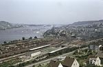 Der Bahnhof Bingerbrück wurde am 15. Juli 1858 zusammen mit dem ersten Teilstück der Nahetalbahn eröffnet. Auf der gegenüberliegenden Flußseite der Nahe lag der Bahnhof Bingen der linksrheinischen Strecke der Hessischen Ludwigsbahnen (oben). Seit dem 17. Oktober 1859 waren mittels einer Eisenbahnbrücke beide Bahnhöfe verbunden. Der Bahnhof Bingerbrück war auch ein Grenzbahnhof zwischen dem damaligen Königreich Preußen zum Großherzogtum Hessen. Zum Bahnhof Bingerbrück gehörte auch der Rangierbahnhof, derr zwischen Personenbahnhof und Rhein lag, ebenso ein großes Bahnbetriebswerk, das rechts oben zu sehen ist. 1993 wurde Bingerbrück in Bingen (Rhein) Hauptbahnhof umbenannt.  (21.08.1955) <i>Foto: Carl Bellingrodt</i>