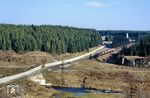 An den erst seit wenigen Wochen funktionslosen Grenzanlagen rollt 99 7234 mit P 14403 Richtung Sorge vorbei. Im Tal verläuft heute die Bundesstraße 242 Richtung Clausthal-Zellerfeld, davor fließt die Warme Bode. Der Fundamentsockel (rechts) gehört zu einer früheren Steinbogenbrücke der ehemaligen Südharz-Eisenbahn, deren Schmalspurstrecke von Tanne nach Braunlage hier die Harzquerbahn überquerte. (21.02.1990) <i>Foto: Wolfgang Bügel</i>