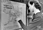 Nach dem Versenden eines fingierten Briefes (vgl. Bild-Nr. 95423) sucht die rumänische Tänzerin Maria Mart nach einem Ziel auf dem U-Bahn-Plan am Potsdamer Bf. Der Zeigefinger befindet sich genau am Standort des Potsdamer Bahnhofs auf der Karte. Interessant sind auch die damaligen Fahrpreise: 15 Pf für drei Stationen. Während der Potsdamer Personenbahnhof, wie der daneben gelegene Anhalter Bahnhof heute komplett verschwunden sind, verlaufen oberhalb des ehemaligen Potsdamer Güterbahnhofgeländes weiterhin die U-Bahn-Linien U1/U3 auf einer Hochbahntrasse sowie die Linie U2 auf einer gesonderten Trasse.  (09.1942) <i>Foto: RVM (Pragher)</i>