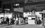 Bei den Luftangriffen auf München im Zweiten Weltkrieg wurde auch der Bahnhof schwer getroffen. Vom 16. Mai bis zum 16. August 1949 wurde die einsturzgefährdete Bahnsteighalle erst gesprengt und dann die restlichen Gebäuderuinen abgerissen, um einen Wiederaufbau zu ermöglichen. Die 140 m breite Halle über den Gleisen 11–26 konnte wegen fehlender Finanzierungsmittel nur in zwei Bauabschnitten neu errichtet werden, und zwar 1950 und 1959/60, jedoch mit 220 m Länge deutlich länger als früher. 1951 eröffnete im Südteil des Bahnhofs das "Bundesbahn-Hotel". Die hier zu sehende neue Schalterhalle war 1953 wieder eröffnet worden. (08.1953) <i>Foto: Karl Wyrsch, Slg. D. Ammann</i>