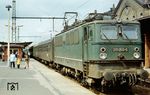 Während die Bremsprobe am Schnellzug D 634 über Halle(Saale) - Köthen nach Magdeburg auf dem Bahnsteig 6 des Erfurter Hbf abgeschlossen wird, zeigt eine Oma ihren interessierten Enkeln die Eisenbahn. Hinter der noch grünen Lok 211 050 vom Bw Magdeburg befinden sich Modernisierungswagen, eine Vorstufe der Reko-Wagen. (30.06.1982) <i>Foto: Thomas Fischer</i>